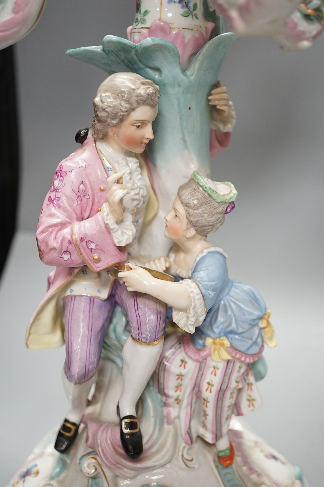 A pair of late 19th century German floral encrusted, figurative porcelain candelabra, 52 cms high.